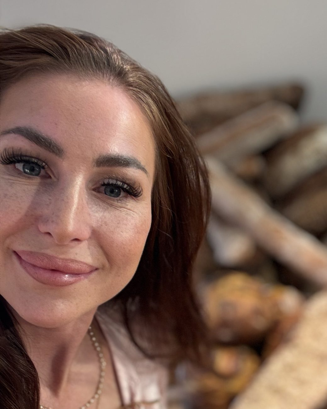 Felicitas lächelnd vor einem Berg frisch gebackener Brote