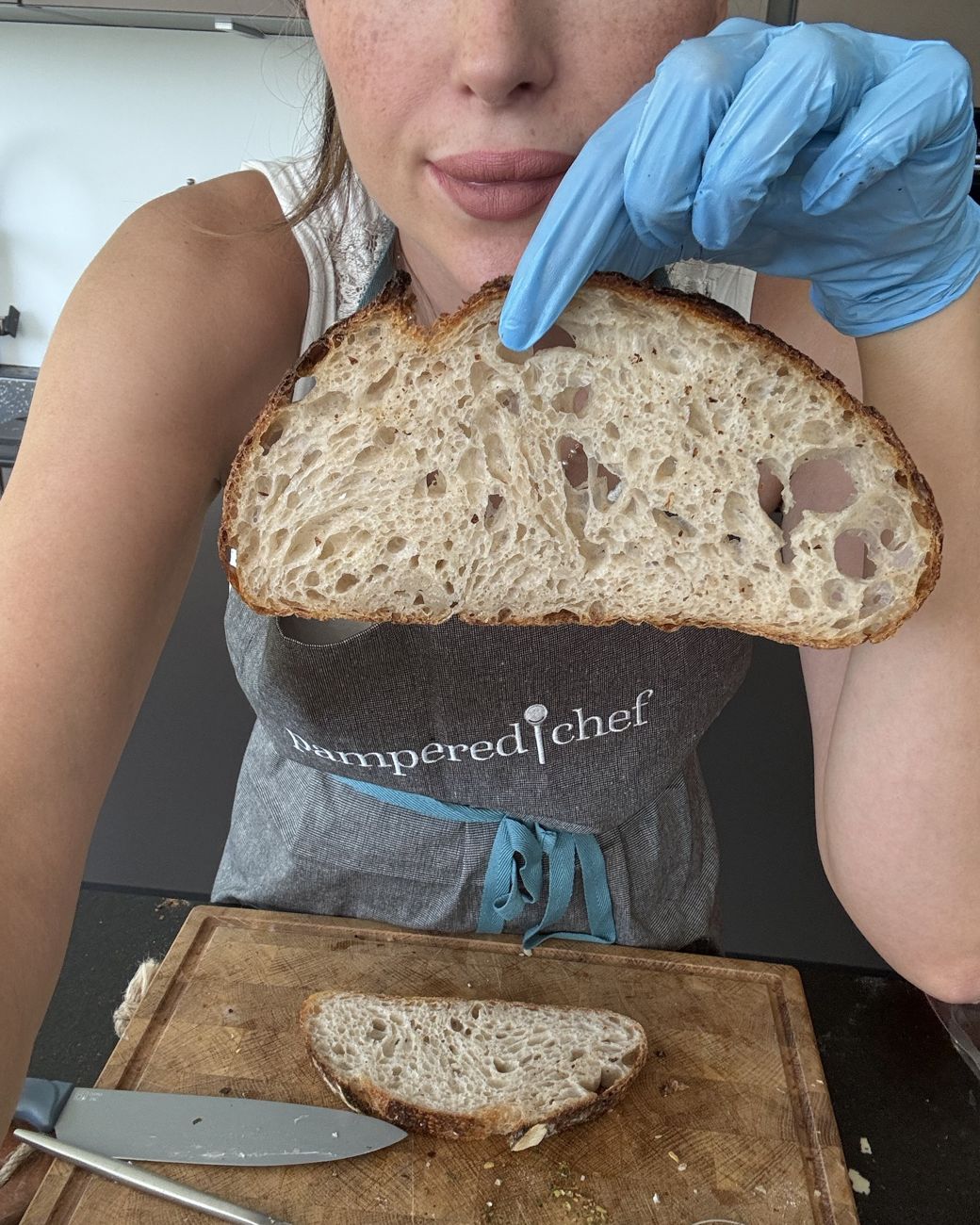 Felicitas in Pampered-Chef-Schürze zeigt eine Scheibe Sauerteigbrot